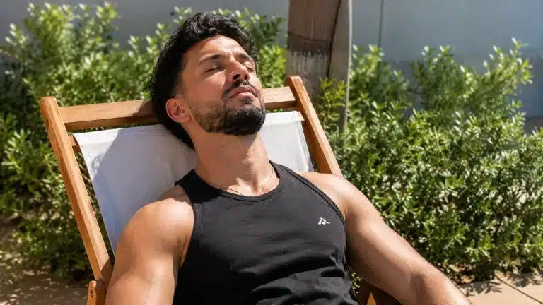 Homme musclé en débardeur qui bronze sur un transat pendant ses vacances d'été