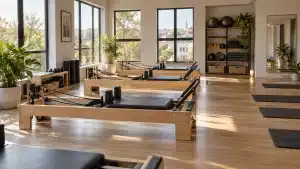 Salle de Pilates lumineuse avec reformers en bois, tapis et accessoires rangés
